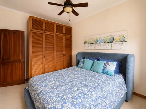 Bedroom with a queen bed, wood wardrobe closet, and bird artwork above the headboard
