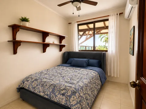 Bedroom 4 with a full-size bed, navy floral bedding, and a wall-mounted display shelf
