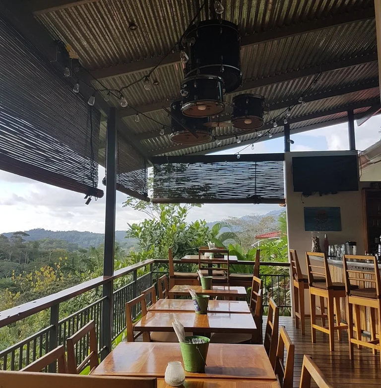 The Bamboo Room’s covered terrace overlooking the jungle hills, with a drum-kit light fixture overhead