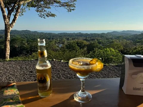 A cocktail and a beer on a table overlooking the jungle and Pacific horizon at La Pala