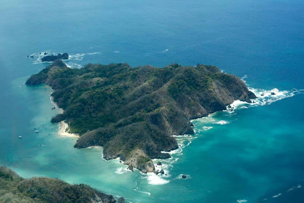 Aerial view of Caño Island’s forested coastline and turquoise water, a protected marine reserve