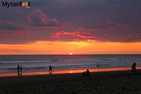 Silhouettes of surfers and beachgoers on Dominical beach at a fiery orange sunset