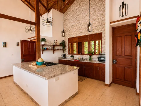 Kitchen with a granite island, wood cabinetry, and industrial pendant lights against a stacked-stone accent wall