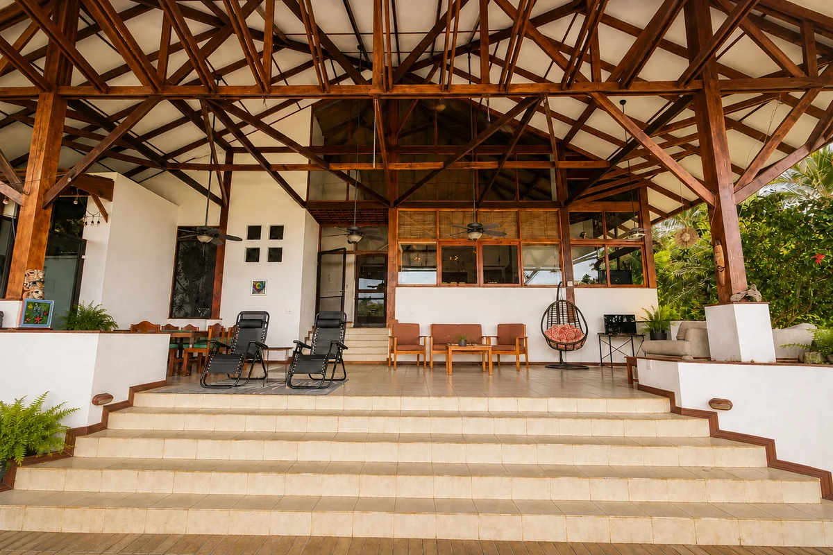 Wide view of the covered terrace steps with lounge chairs and seating, opening onto the kitchen and hanging egg chair beyond