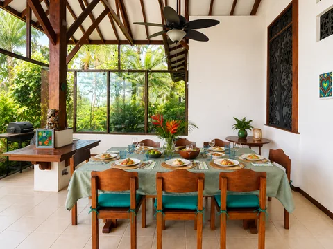 Outdoor dining table set for a meal with a heliconia flower centerpiece and jungle view