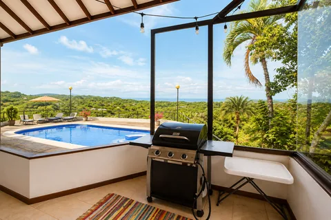 Outdoor grill area with a view over the pool toward the ocean