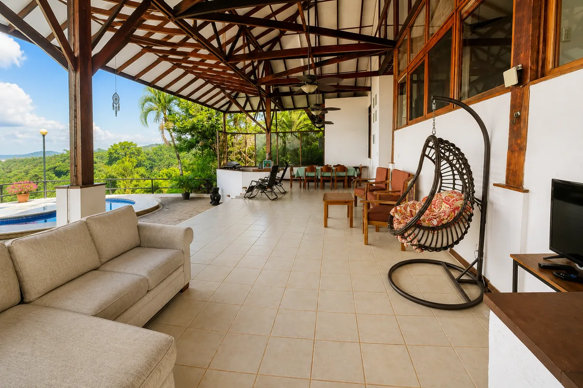 Panoramic view of the covered pavilion with the pool, sectional sofa, dining table, and egg chair