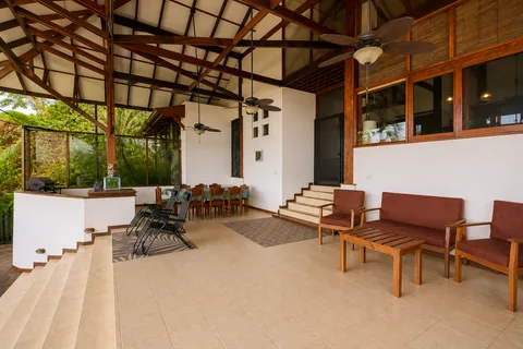Wide view of the covered pavilion showing the grill, dining table, and lounge seating together