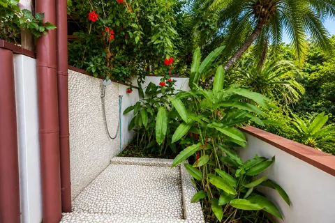 Outdoor shower surrounded by tropical plants and hibiscus flowers